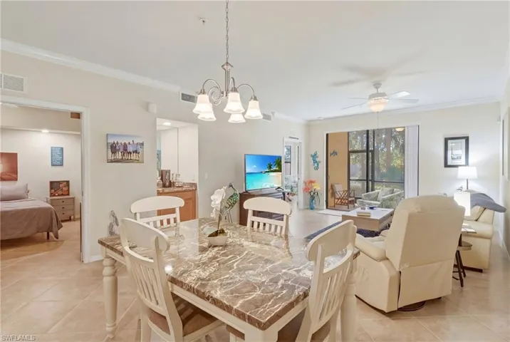 Dining room with ornamental molding, ceiling fan, a chandelier, and light tile patterned flooring
