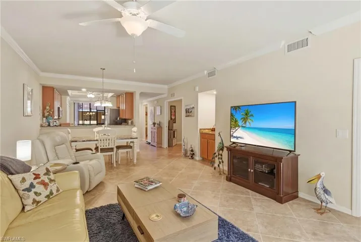 Living area with ceiling fan, crown molding, and light tile patterned flooring