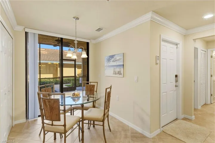 Dining room with ornamental molding, suspended lighting, floor to ceiling windows, and light tile patterned floors