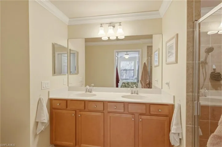 Bathroom with double vanity, a stall shower, and crown molding