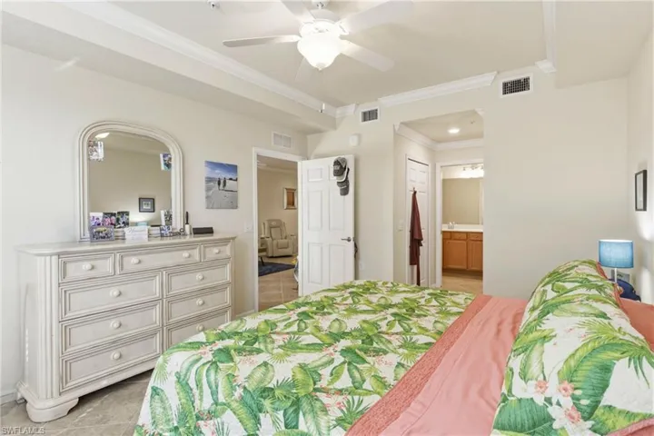 Bedroom featuring ornamental molding, ceiling fan, light tile patterned floors, and connected bathroom