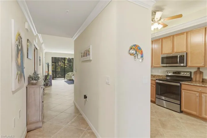 Kitchen with stainless steel appliances, a ceiling fan, crown molding, light tile patterned floors, and light wood finish cabinetry