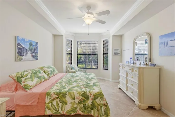 Bedroom with ornamental molding, a ceiling fan, and light tile patterned flooring