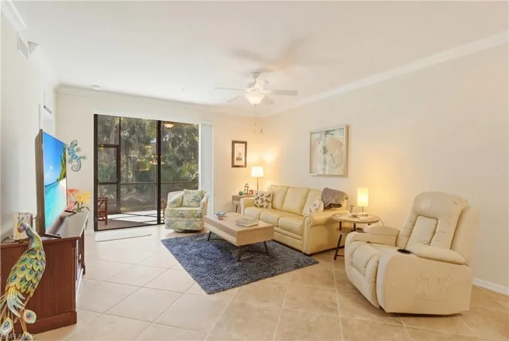 Living area with a ceiling fan, crown molding, and light tile patterned flooring