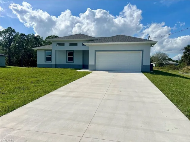View of front of house featuring a front lawn and a garage and extra long driveway for plenty of parking