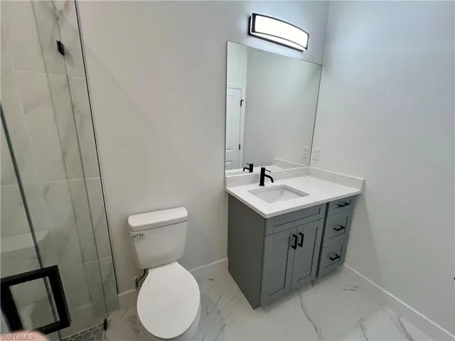 Bathroom featuring vanity, toilet, and an enclosed shower