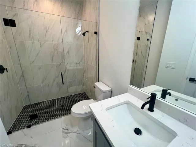 Bathroom with a shower with door, vanity, and toilet