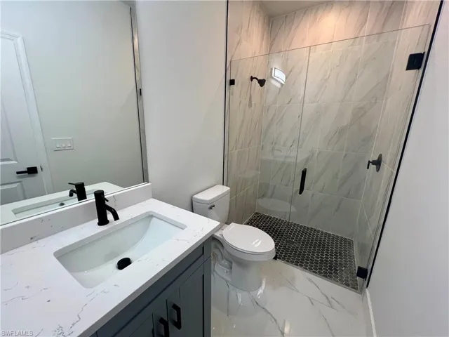 In law bathroom with vanity, a shower with glass shower door, and toilet