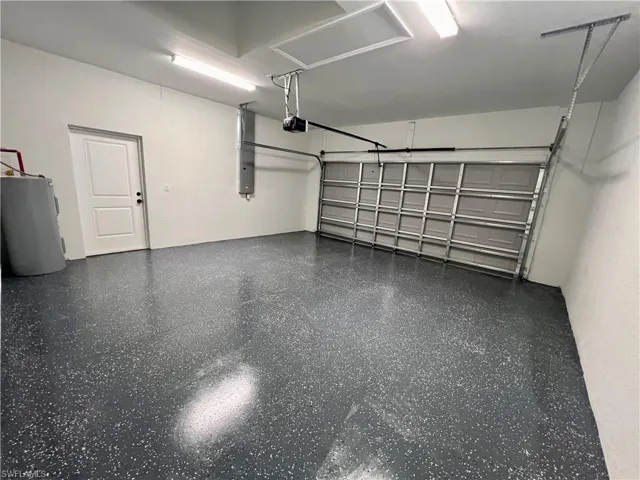 Garage featuring a garage door opener  electric water heater and seal coated floor