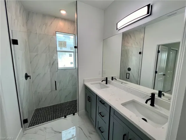 Bathroom with a glass shower with door and dual vanities