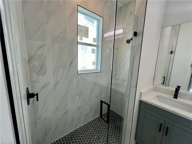 Bathroom with a tile shower, glass doors and  and vanity