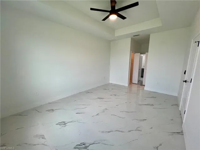 Primary bedroom with ceiling fan and a raised ceiling