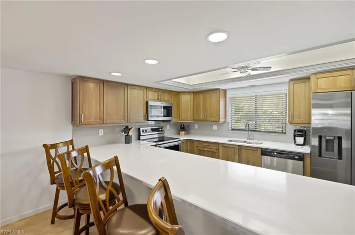 Kitchen featuring light countertops, appliances with stainless steel finishes, decorative backsplash, and a sink