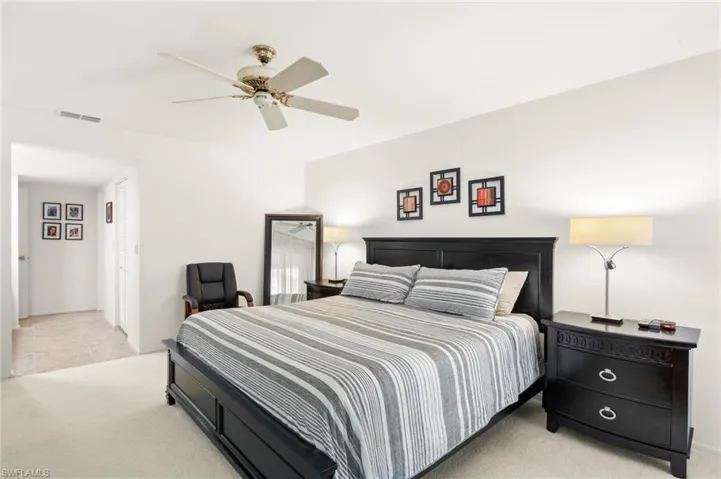 Carpeted bedroom featuring ceiling fan, visible vents, and tile patterned floors