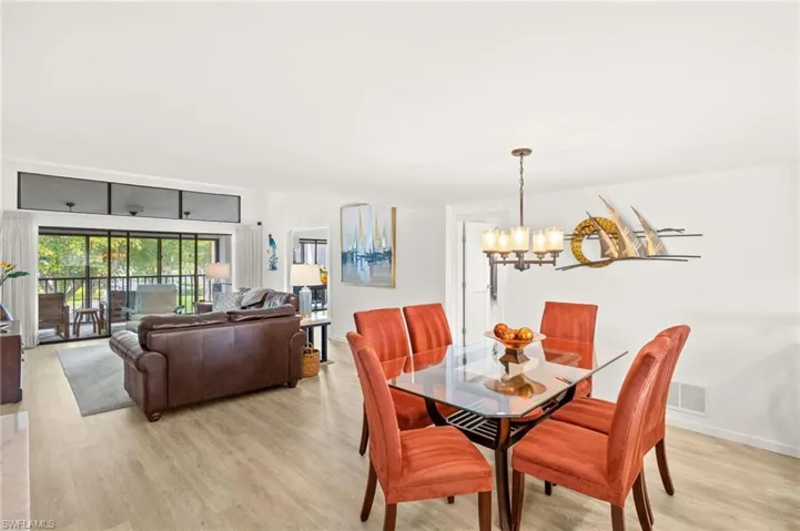 Dining area featuring light wood finished floors, baseboards, a notable chandelier, and visible vents