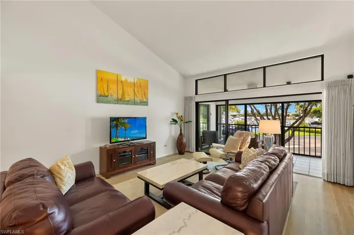 Living area with light wood-type flooring, baseboards, and high vaulted ceiling