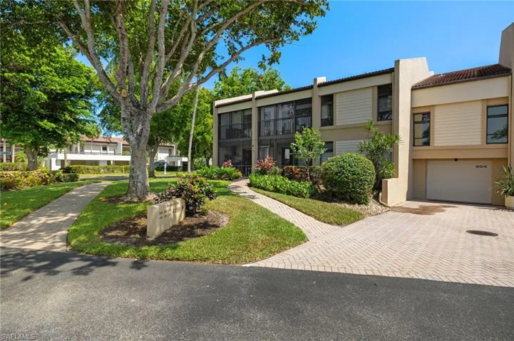 View of property featuring a tile roof, stucco siding, a garage, and decorative driveway