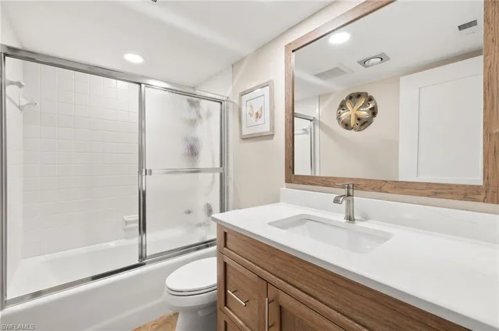 Full bath with vanity, visible vents, toilet, and enclosed tub / shower combo