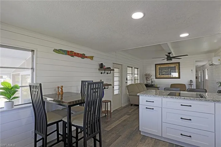 Dining space featuring a textured ceiling, wood walls, dark wood-style flooring, recessed lighting, and ceiling fan