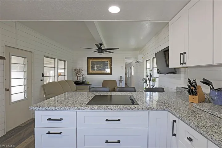 Kitchen with white cabinets, light stone countertops, a peninsula, open floor plan, and a textured ceiling