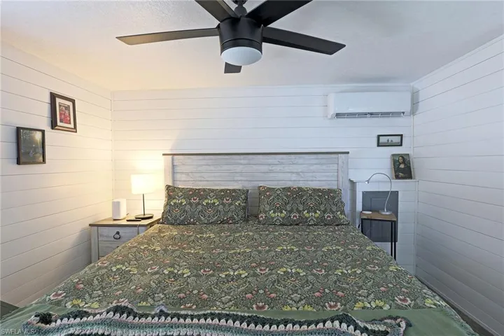 Bedroom featuring a wall unit AC, ceiling fan, and wooden walls