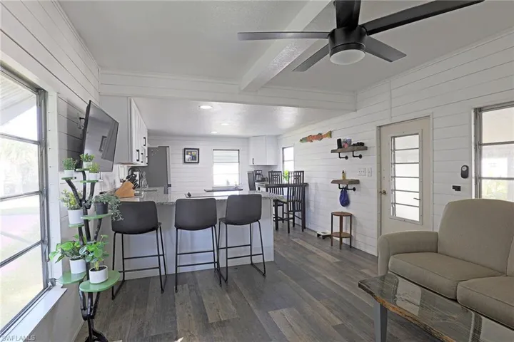 Kitchen featuring white cabinets, a breakfast bar area, wood walls, a peninsula, and dark wood-type flooring