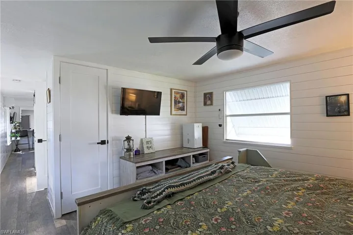 Bedroom featuring a textured ceiling, ceiling fan, wood finished floors, and wood walls