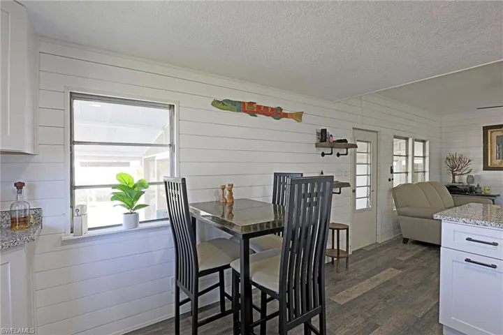 Dining room featuring dark wood finished floors, a textured ceiling, wood walls, and plenty of natural light