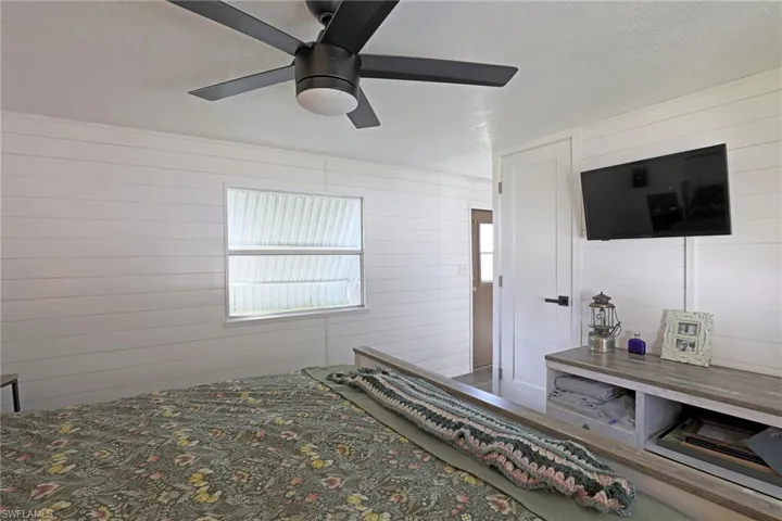 Bedroom with ceiling fan, a textured ceiling, and wood walls
