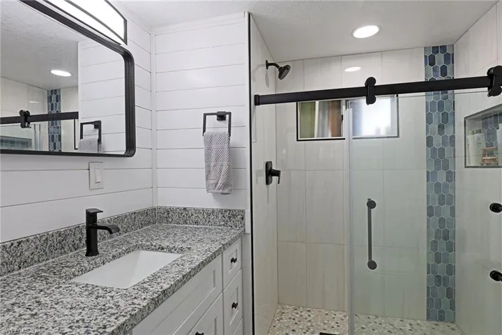 Full bath with vanity, a textured ceiling, a stall shower, and recessed lighting