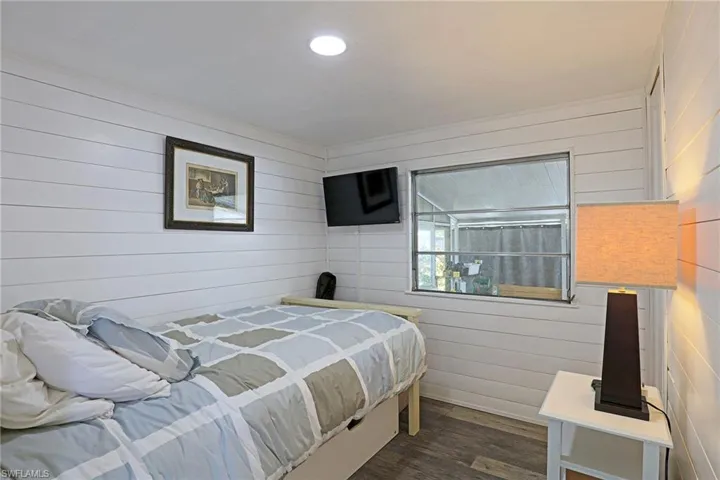 Bedroom featuring wood walls, dark wood-style floors, and recessed lighting