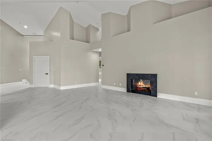 Unfurnished living room featuring a high ceiling and a high end fireplace