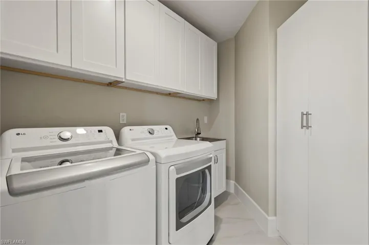 Laundry room with cabinets, washing machine and dryer, and sink