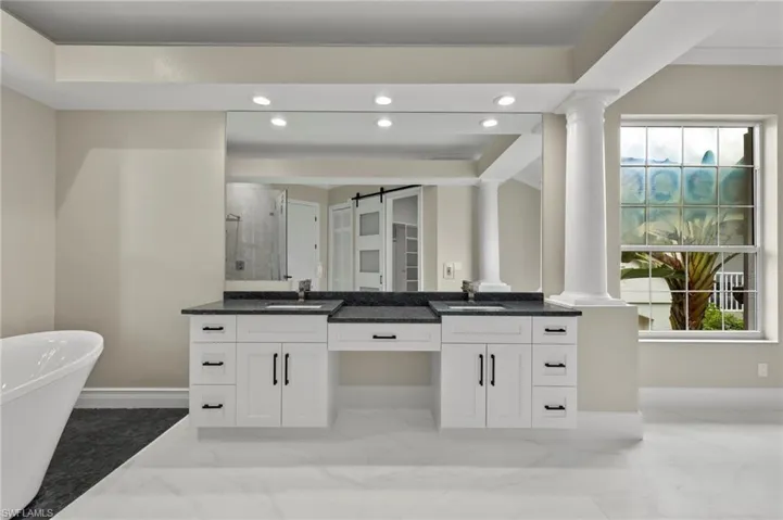 Bathroom featuring crown molding, vanity, separate shower and tub, and decorative columns