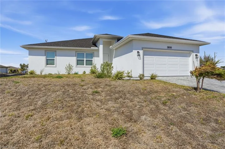 View of front of house with stucco siding, a garage, and decorative driveway