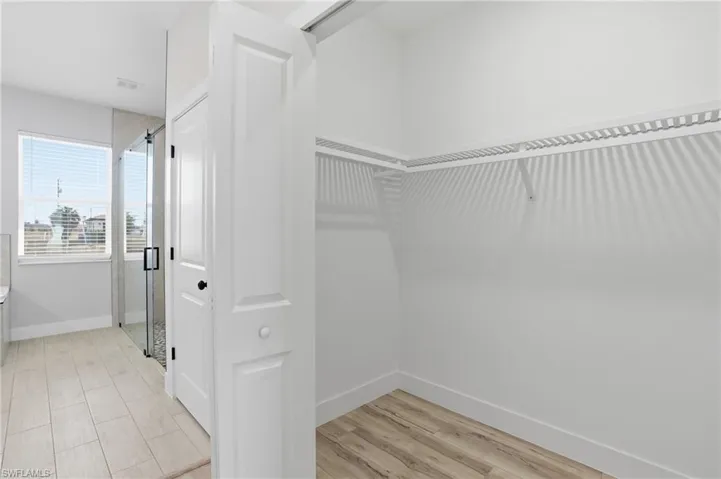 Walk in closet with light wood-style flooring