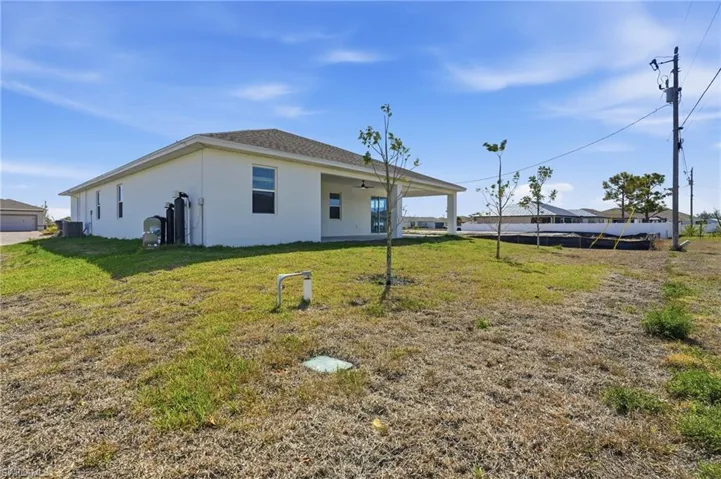 Rear view of property with stucco siding, a patio area, and a lawn