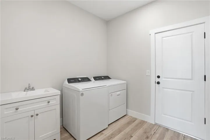 Laundry room featuring light wood-style flooring, independent washer and dryer, and cabinet space