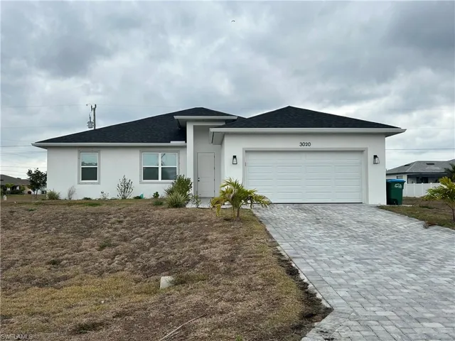 Ranch-style house with decorative driveway, stucco siding, a garage, and a shingled roof