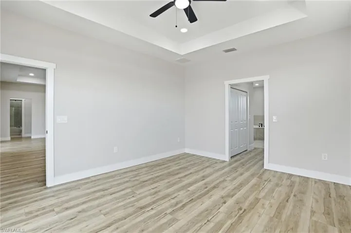 Spare room with a raised ceiling, light wood-style flooring, recessed lighting, and a ceiling fan