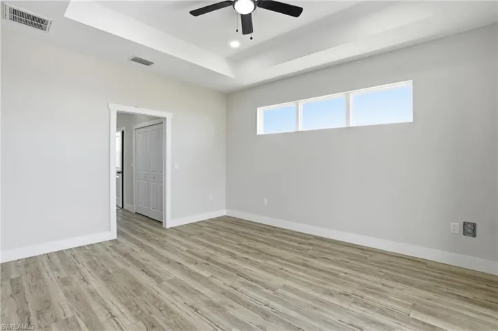 Unfurnished room with a tray ceiling, light wood-style floors, ceiling fan, and recessed lighting