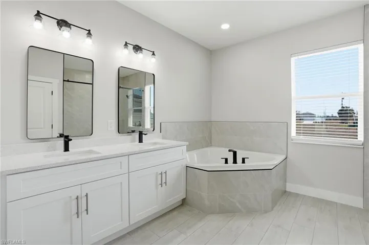 Bathroom with double vanity, a garden tub, plenty of natural light, and recessed lighting