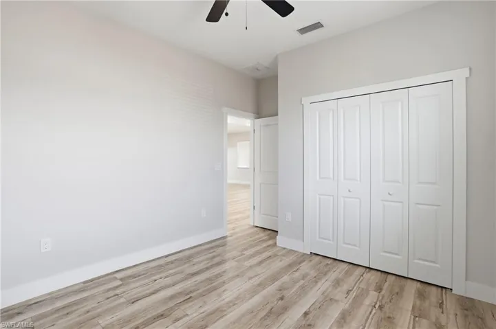 Unfurnished bedroom featuring light wood-style floors, a closet, and ceiling fan
