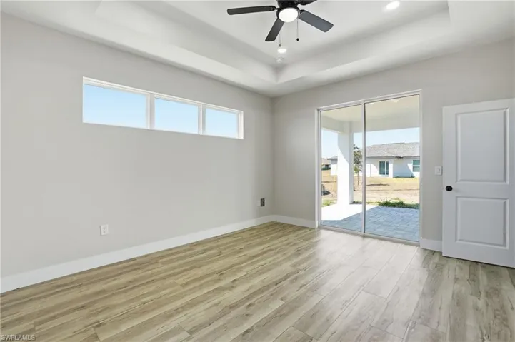 Spare room featuring light wood-type flooring, a raised ceiling, a ceiling fan, and recessed lighting