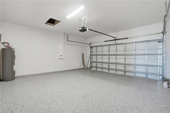 Garage featuring electric water heater, a garage door opener, and electric panel