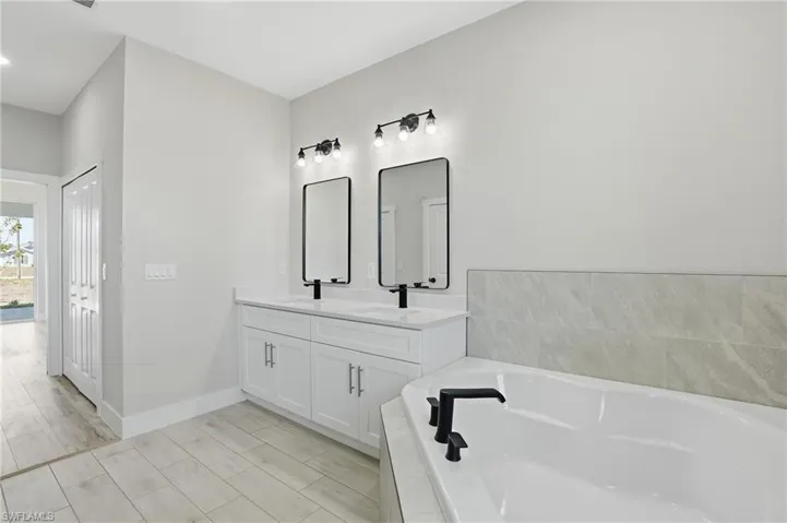 Bathroom with double vanity, a garden tub, and wood finish floors
