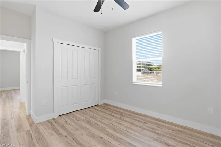 Unfurnished bedroom featuring light wood finished floors, a closet, and a ceiling fan
