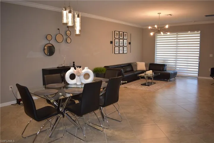 Tiled dining area featuring crown molding and a chandelier