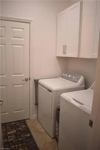Laundry room with washer and dryer, cabinet space, and light tile patterned floors