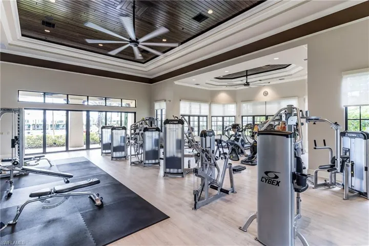 Gym featuring ceiling fan, crown molding, and a tray ceiling